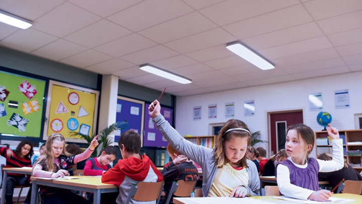Children engrossed in a lesson raise their hands to answer a question from a teacher - optimum learning environment