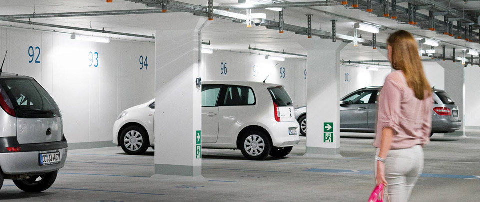 Woman walks to car in well-lit underground car park 