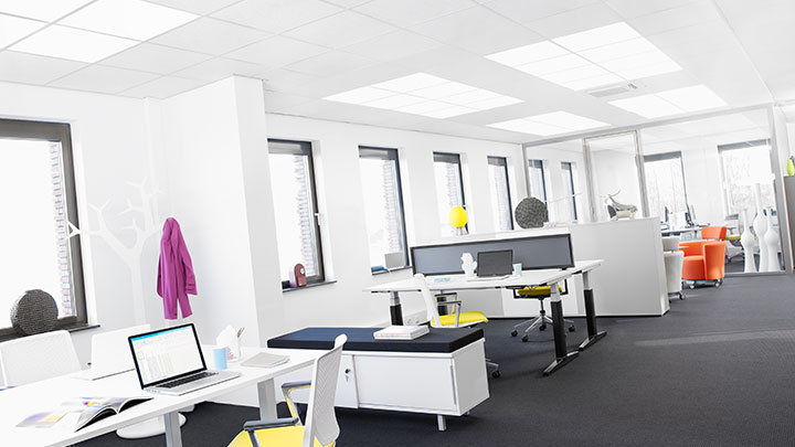 Woman on the phone under Soundlight Comfort solution. Ideal office lighting for more comfortable workplaces.